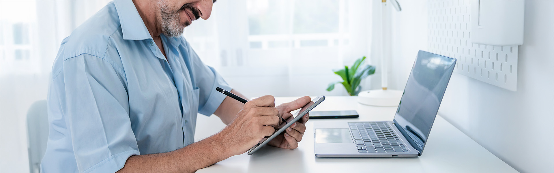 Close up of man in office with digital tablet and laptop