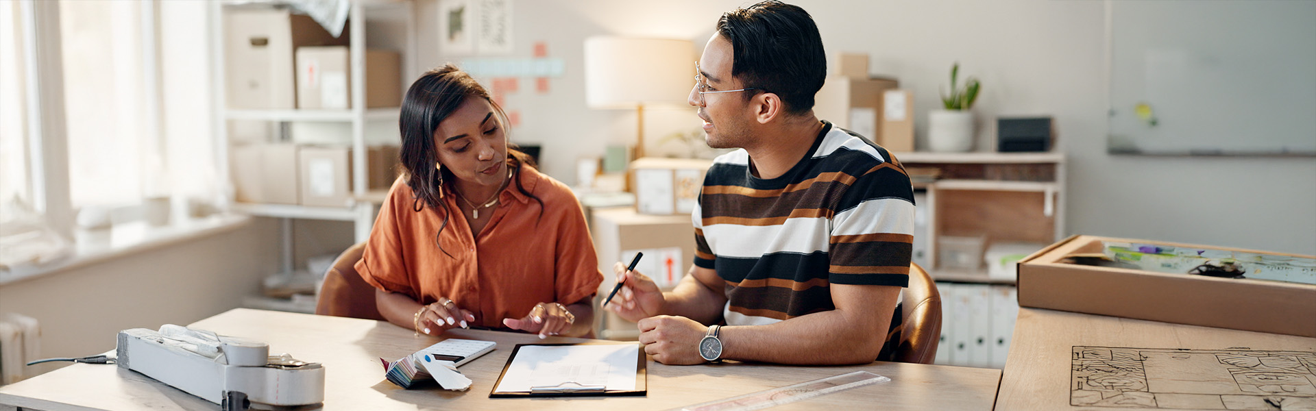 Two people meeting with checklist calculator in an office.
