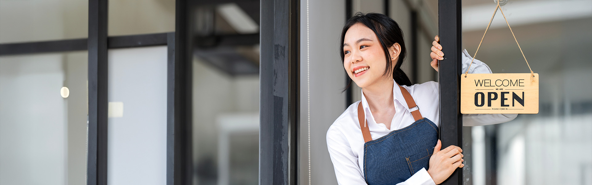 Young Asian woman at door with Open sign